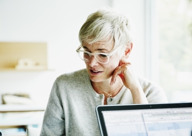 Senior woman looking down at something on table.